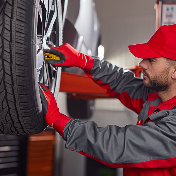 Mechanic with customer checking car wheel